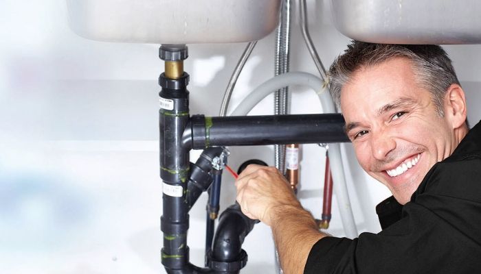 smiling plumbing repairing a sink