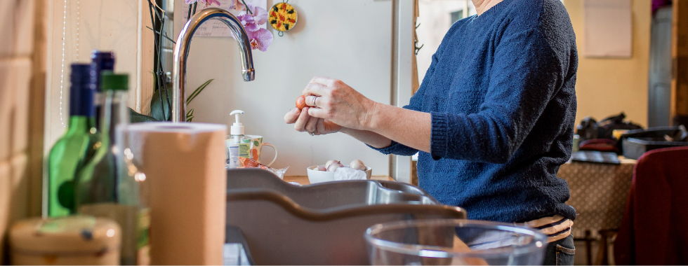 woman at sink peeling vegetables