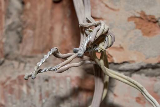 Aluminum wiring with a brick wall behind it.